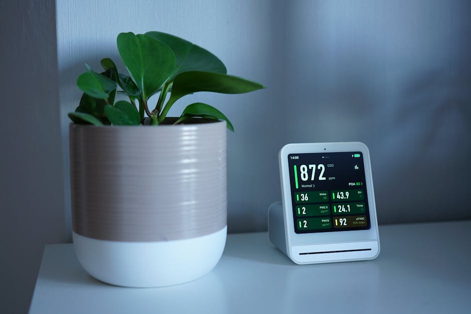 Indoor air quality monitor on a wall near an HVAC vent during an audit
