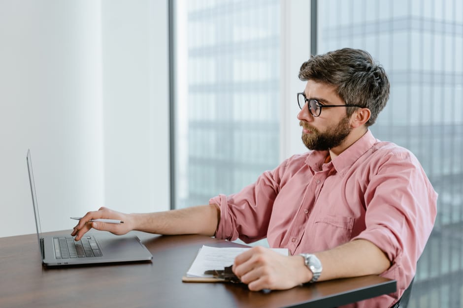 Security analyst reviewing server logs on a laptop in a monitoring workspace