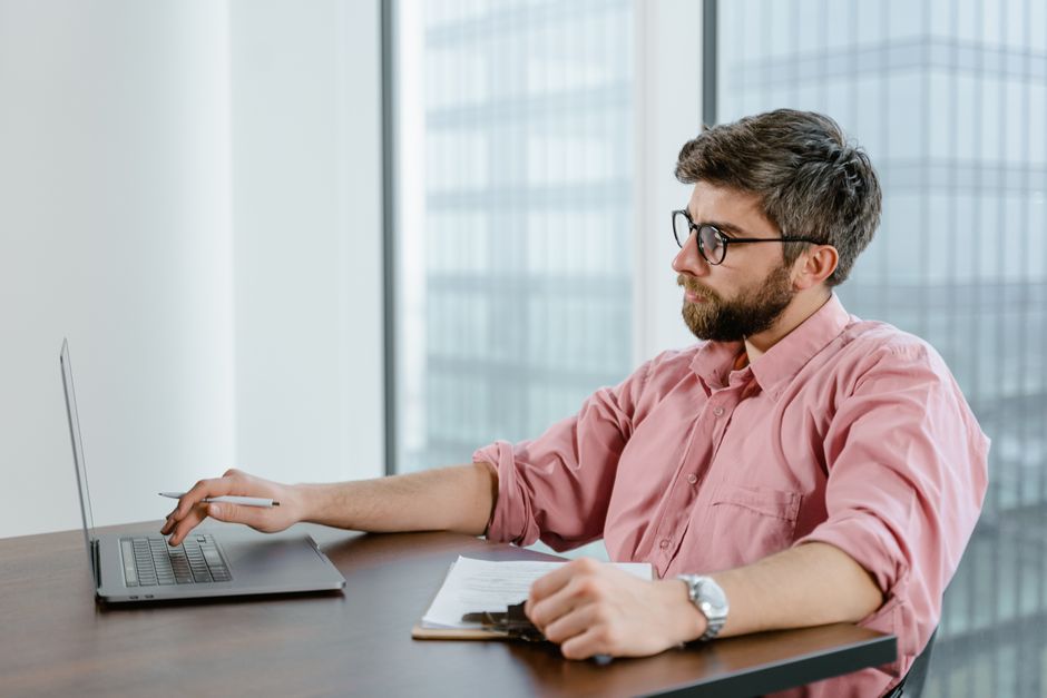 Security analyst reviewing CVE triage notes on a laptop with multiple alerts